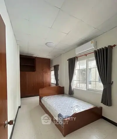 Cozy bedroom with single bed, built-in wardrobe, and air conditioning, perfect for comfortable living.