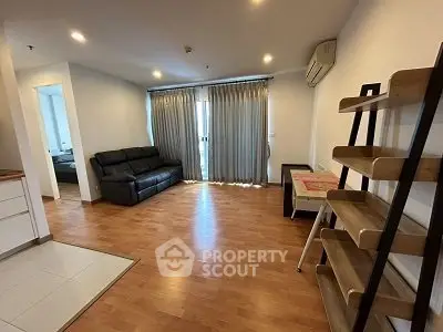 Spacious living room with wooden flooring and modern furniture in a cozy apartment.