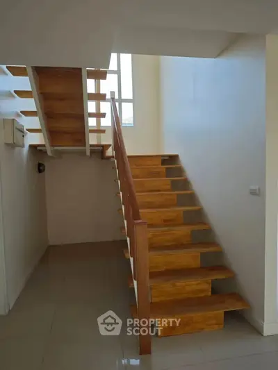 Modern wooden staircase with sleek design and natural light in a contemporary home.