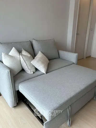 Modern living room with stylish gray sofa bed and decorative pillows in a cozy apartment.