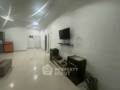 Spacious living room with modern TV setup and sleek tile flooring.