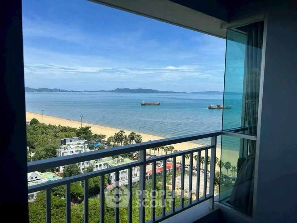 Stunning ocean view from a high-rise balcony overlooking a serene beach and clear blue sky.