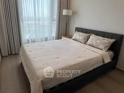 Cozy bedroom with modern decor and large window offering natural light and city views.