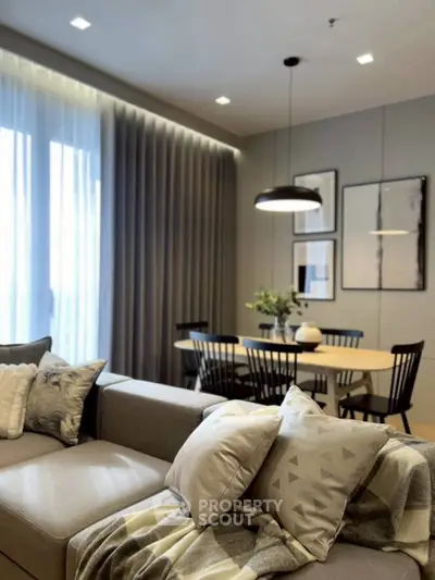 Modern living room with stylish decor and dining area, featuring cozy seating and elegant lighting.