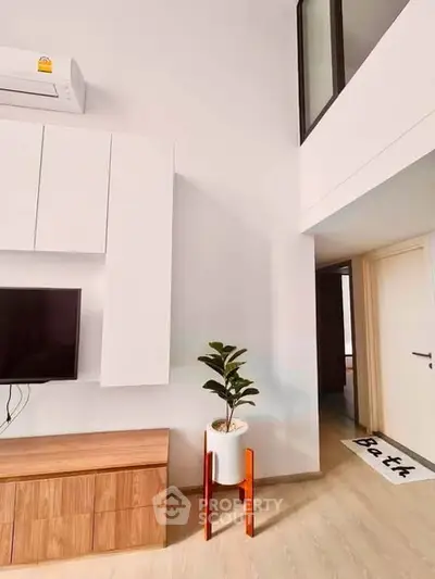 Modern living room with high ceiling, stylish furniture, and indoor plant for a cozy ambiance.