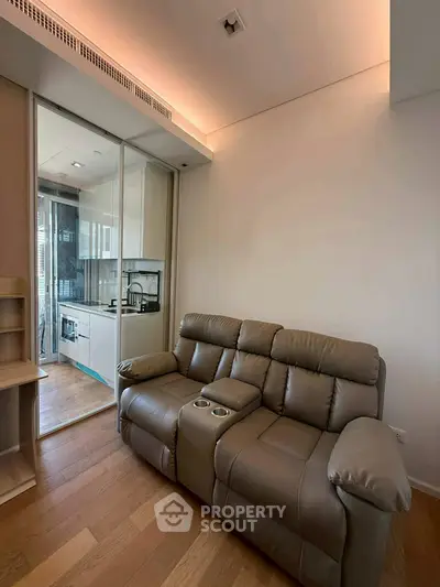 Modern living room with leather sofa and sleek kitchen view.