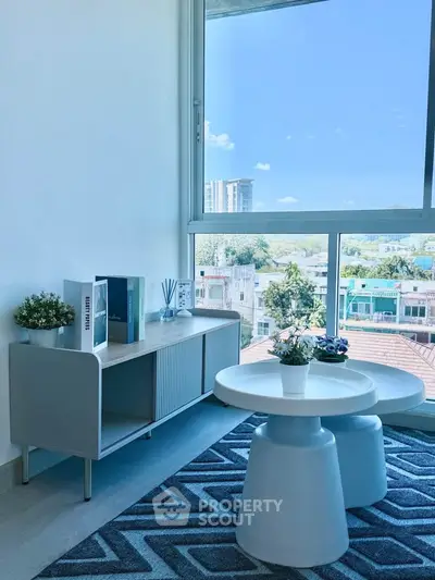Bright living room with modern furniture and large window offering stunning city view.