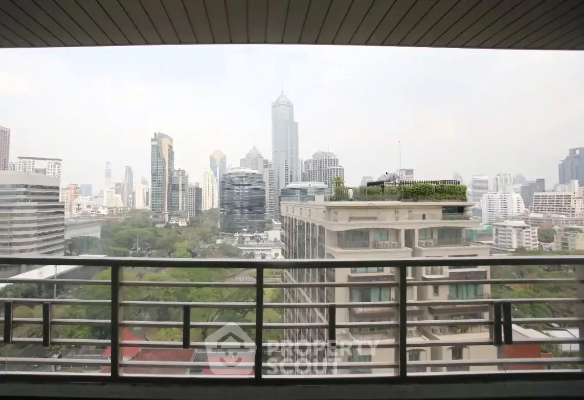 Stunning cityscape view from a high-rise balcony overlooking urban skyline and lush greenery.