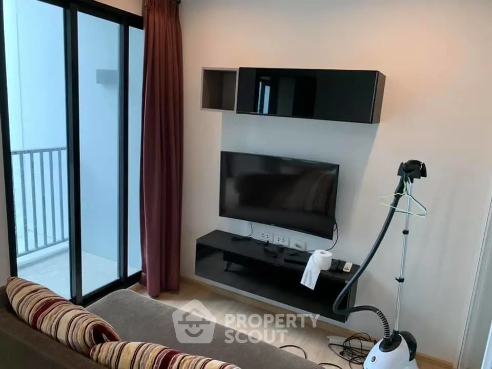 Modern living room with sleek TV setup and balcony access in stylish apartment.