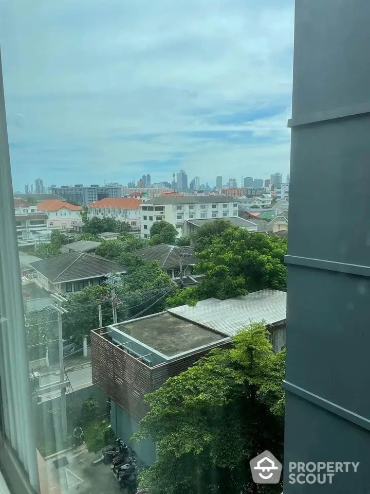 Stunning urban view from a high-rise window overlooking cityscape and greenery.