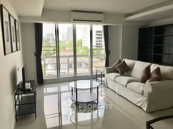 Spacious living room with modern decor and large windows offering city views.