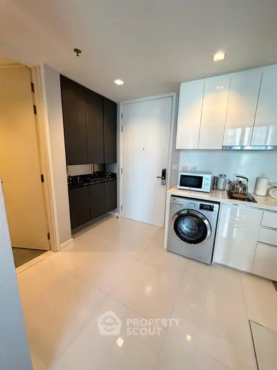 Modern kitchen with sleek appliances and integrated washing machine in a stylish apartment.