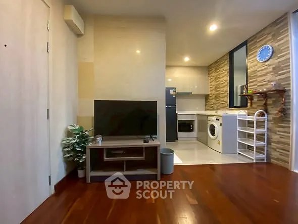 Modern living room with open kitchen, hardwood floors, and stylish decor