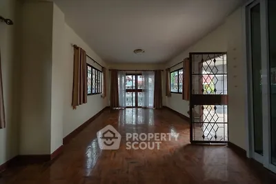 Spacious living room with large windows and wooden flooring, perfect for natural light and comfort.