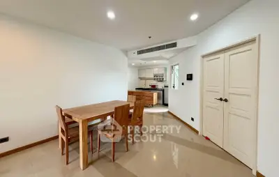 Spacious dining area with wooden furniture and modern kitchen in open layout apartment.