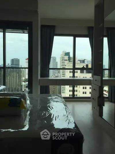 Modern bedroom with city view and large windows in high-rise apartment