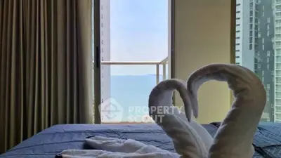 Luxurious bedroom with stunning balcony view and elegant towel swans on bed.