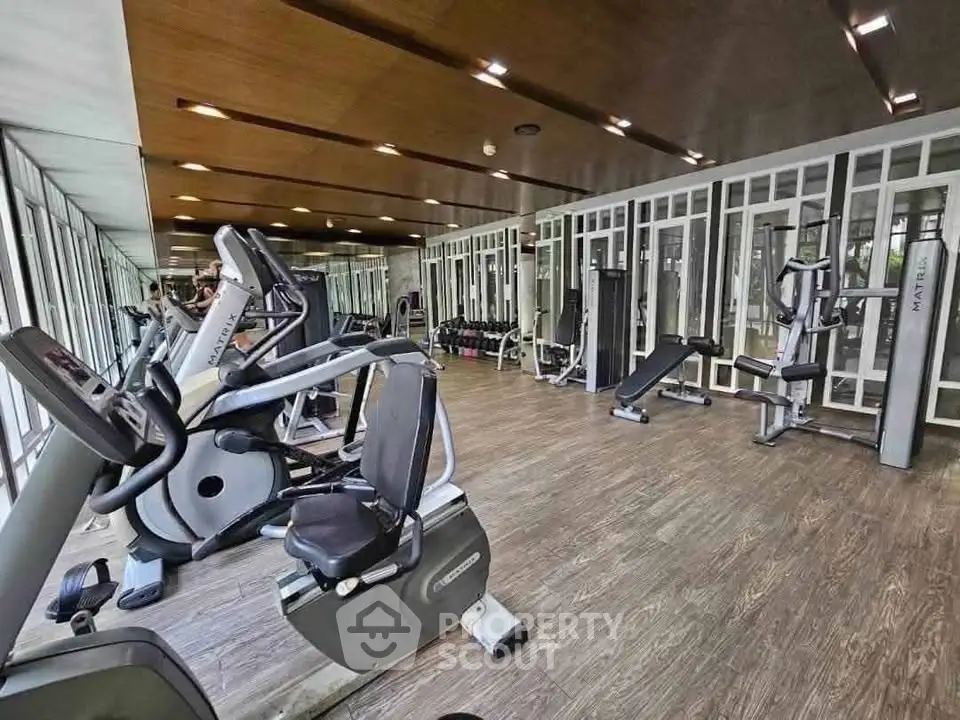 Modern gym with state-of-the-art fitness equipment and mirrored walls in a luxury building.