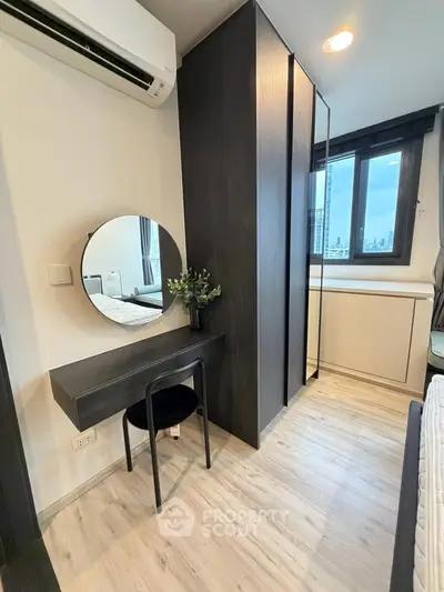 Modern bedroom with sleek design, featuring a stylish vanity and large window with city view.