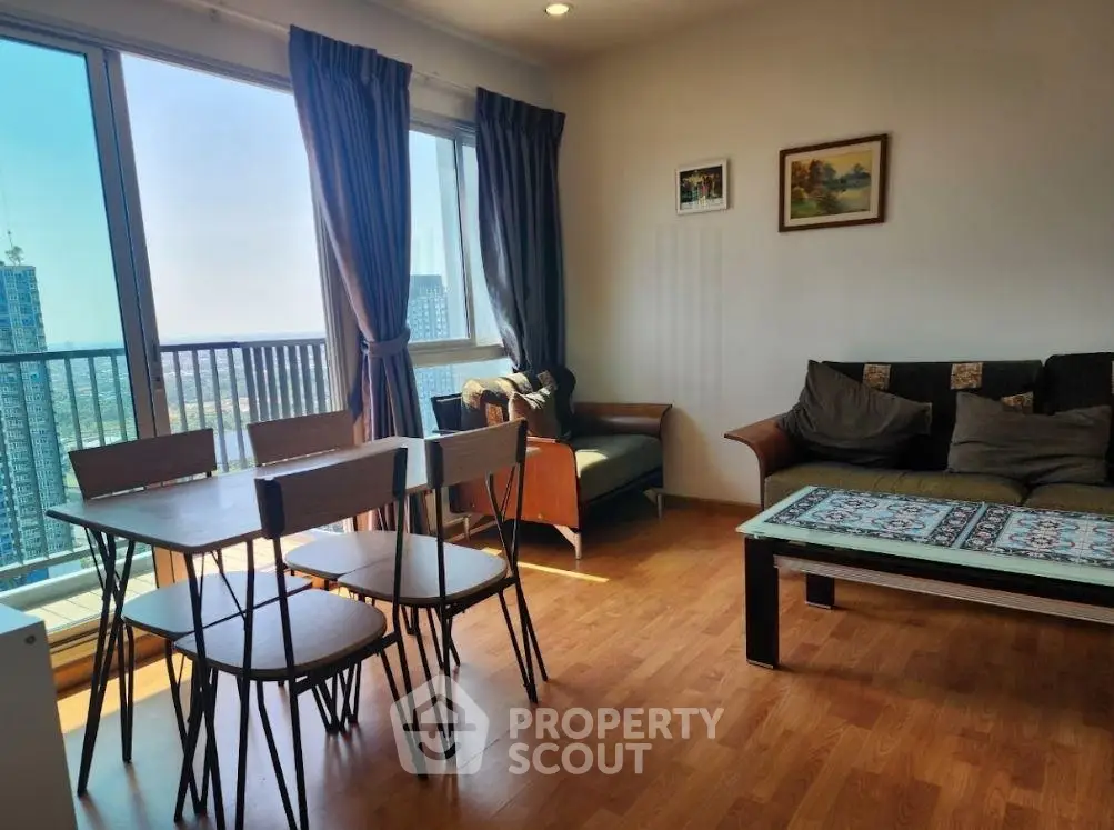 Spacious living room with balcony and city view, featuring modern furniture and wooden flooring.