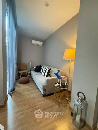 Cozy living room with modern decor and natural light, featuring a comfortable sofa and stylish lamp.