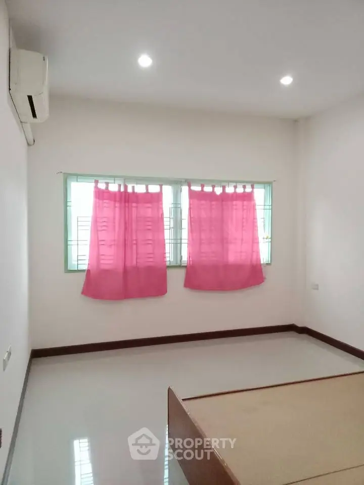 Spacious bedroom with pink curtains and air conditioning, perfect for a cozy living space.