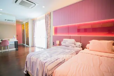 Luxurious bedroom with twin beds, elegant decor, and ample natural light