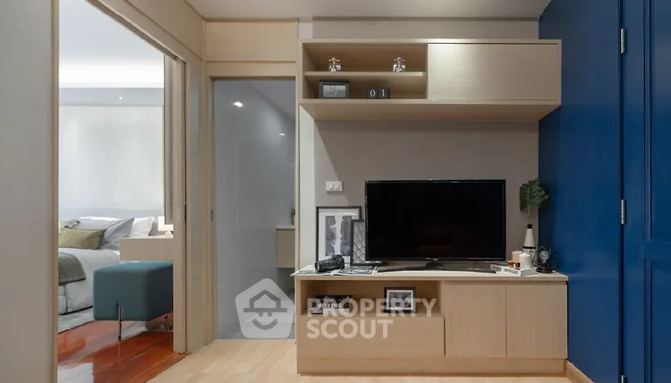 Modern living room with TV unit and view into bedroom