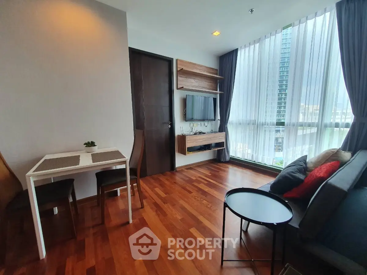 Modern living room with hardwood floors, large windows, and stylish furniture in a high-rise apartment.