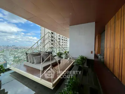 Luxurious balcony with stunning city view and modern seating area in high-rise building.