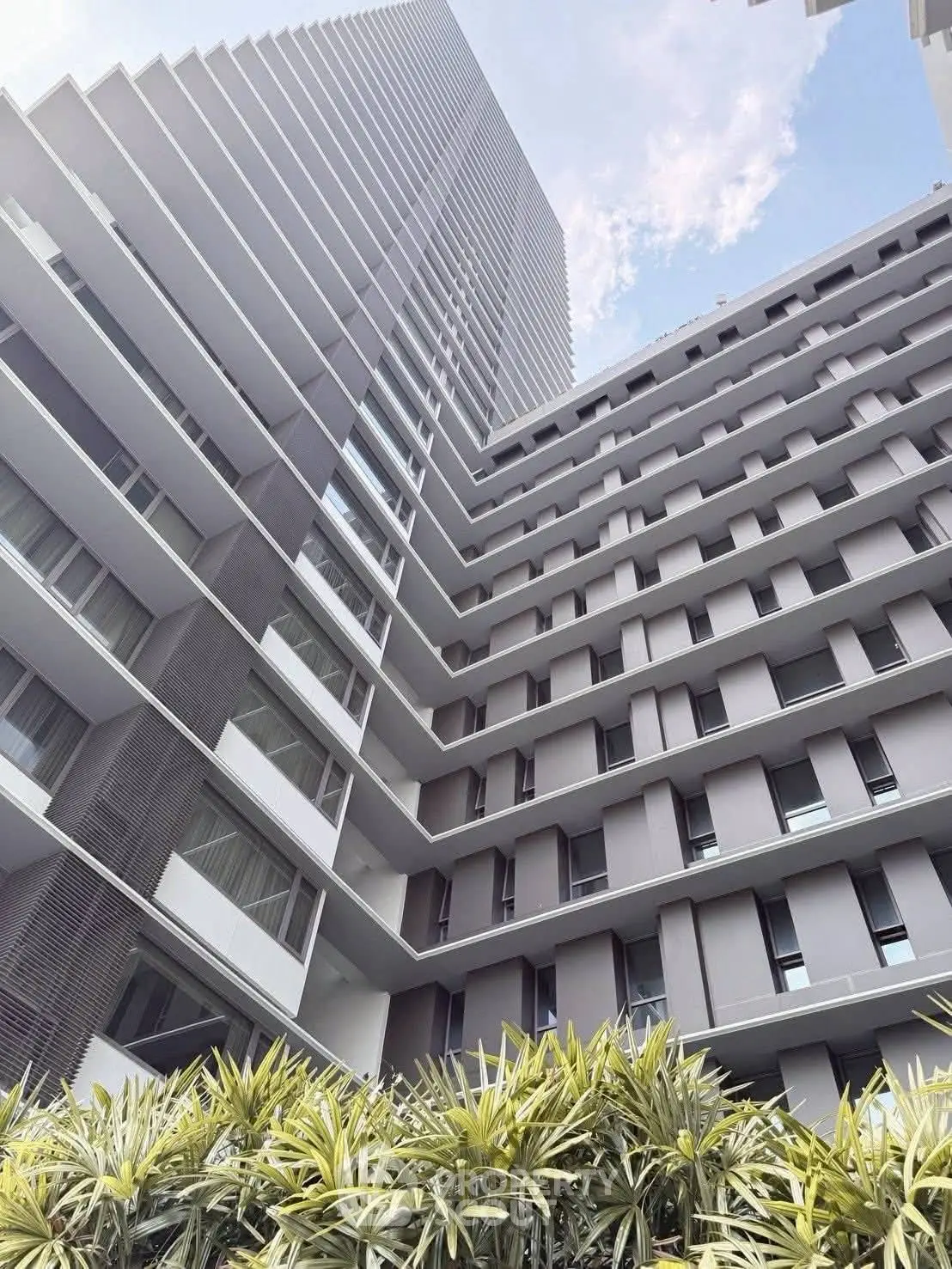 Modern high-rise building with sleek architectural design and lush greenery