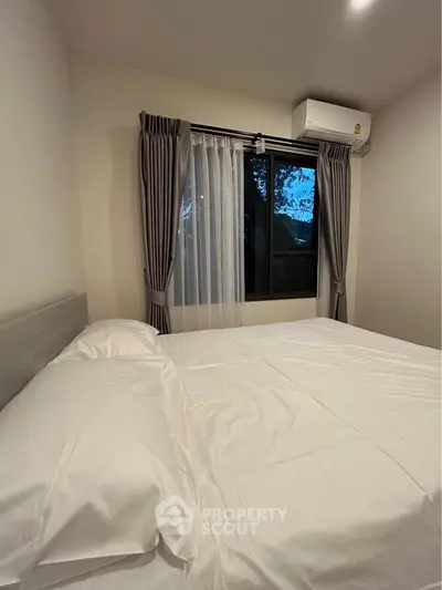 Cozy bedroom with large window and air conditioning unit, perfect for relaxation.