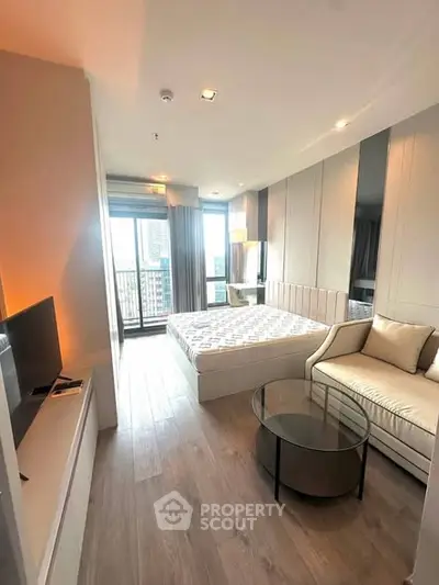 Modern bedroom with cozy seating area and city view balcony in luxury apartment.