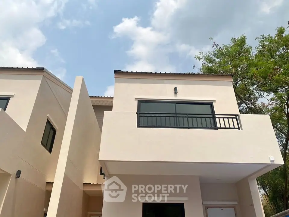 Modern two-story house exterior with clean lines and large windows under a clear blue sky.
