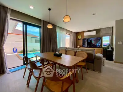 Modern living room with pool view, stylish furniture, and natural light.