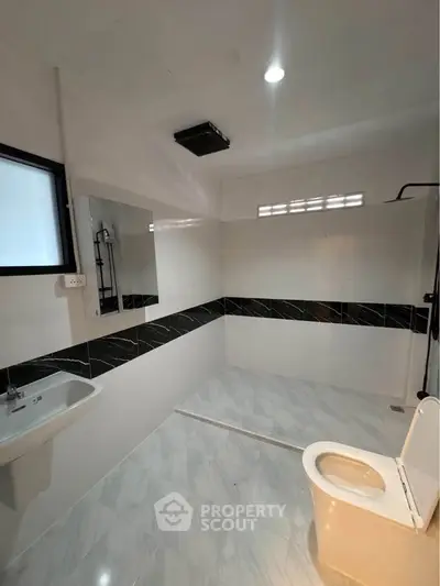 Modern bathroom with sleek black and white tiles, featuring a shower and contemporary fixtures.
