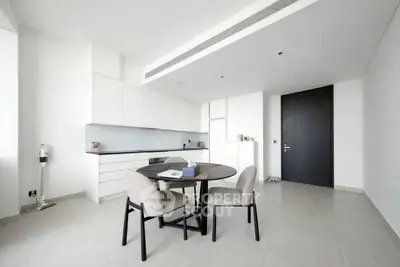 Modern minimalist kitchen with sleek white cabinets and round dining table in a bright open space.