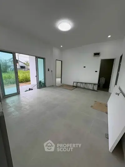 Spacious unfurnished room with large windows and modern tile flooring, ideal for customization.