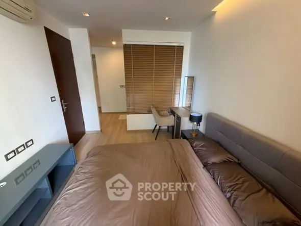 Modern bedroom with stylish decor and natural light, featuring a cozy bed and sleek furniture.