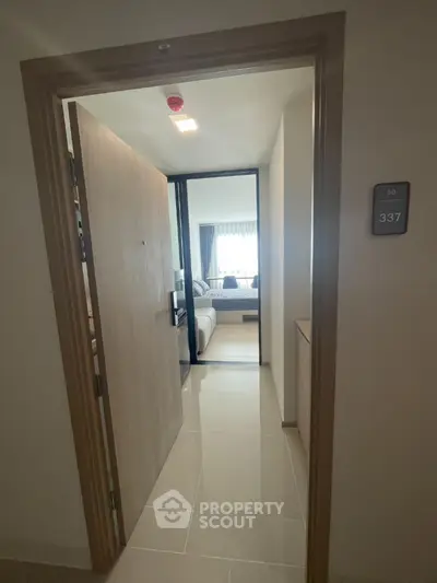 Modern apartment entrance with open door leading to a cozy bedroom