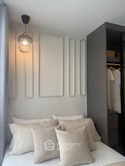Modern bedroom with stylish wall decor and cozy pillows, featuring a sleek open wardrobe design.