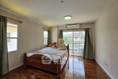 Spacious bedroom with wooden flooring and large window for natural light