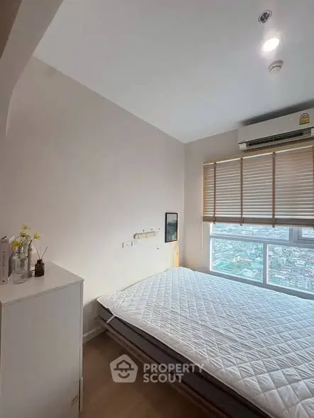 Bright bedroom with city view, featuring a comfortable bed and modern decor.