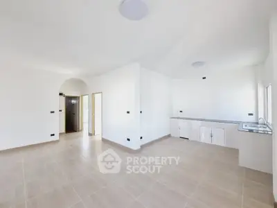 Spacious open-plan room with modern kitchen and ample natural light.