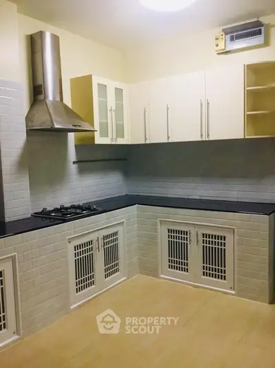 Spacious kitchen with modern gas stove and ample storage cabinets.