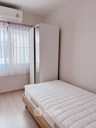 Cozy bedroom with natural light and minimalist design, featuring a comfortable bed and air conditioning.