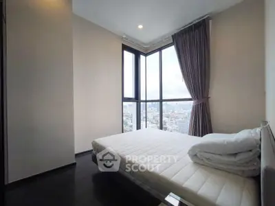 Modern bedroom with panoramic city view and large windows in a high-rise apartment.