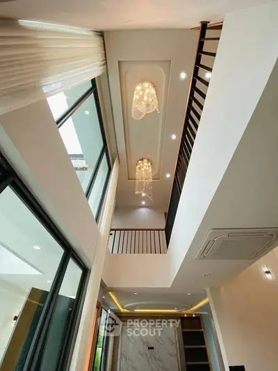 Luxurious modern interior with high ceilings and elegant chandeliers in a spacious living area.