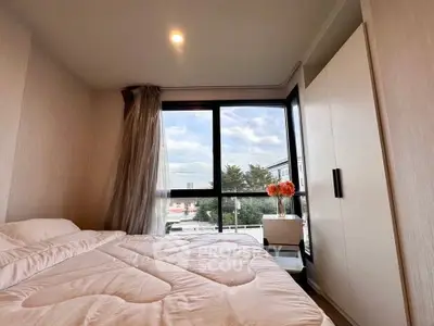 Cozy bedroom with large window offering a scenic view, modern wardrobe, and elegant decor.