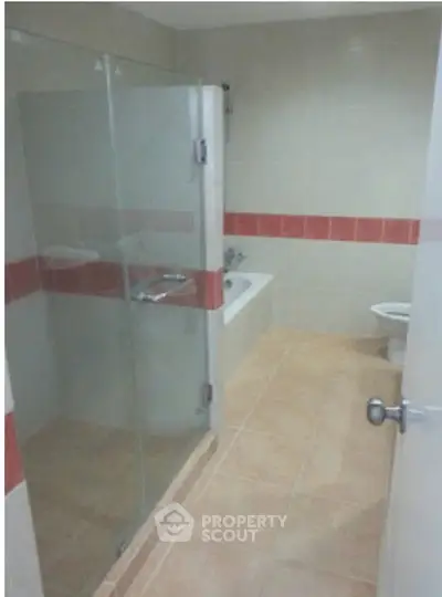 Modern bathroom with glass shower and bathtub in stylish apartment.